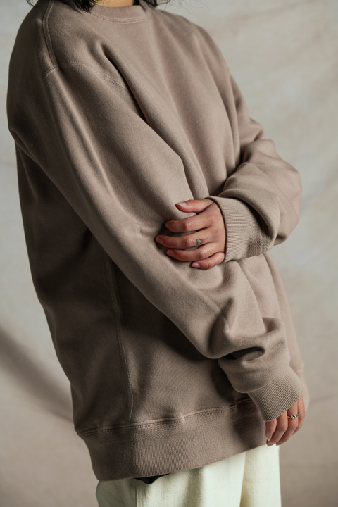 157cm female model wearing 44 fleece everyday crewneck sweatshirt in mauve by Lady White Co. Left arm is across her body and holding onto her right elbow. Close up of her torso showing an oversized, long fit. 
