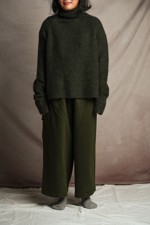 157cm female model standing and wearing Mónica Cordera chunky cotton pocket pant in green. Paired with Mónica Cordera soft alpaca turtleneck in green