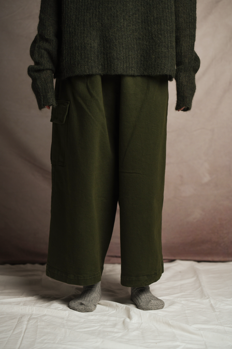 Close up of lower leg of model standing and wearing Mónica Cordera chunky cotton pocket pant in green. Paired with Mónica Cordera soft alpaca turtleneck in green