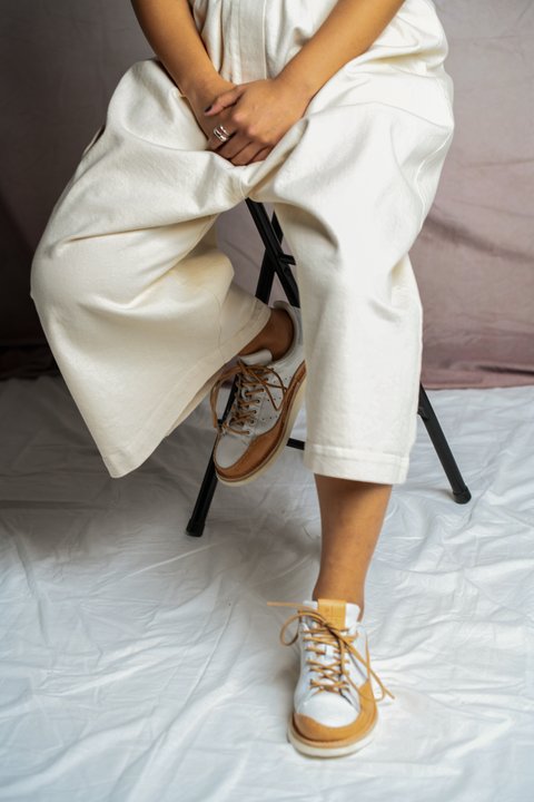 Person seated wearing the Mónica Cordera Chunky Cotton Pocket Pants in Natural and Peterson Stoop Stan Smith Wavy shoes