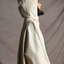Side view of female standing wearing the hood on the Mónica Cordera chunkyu hooded poncho in natural. 