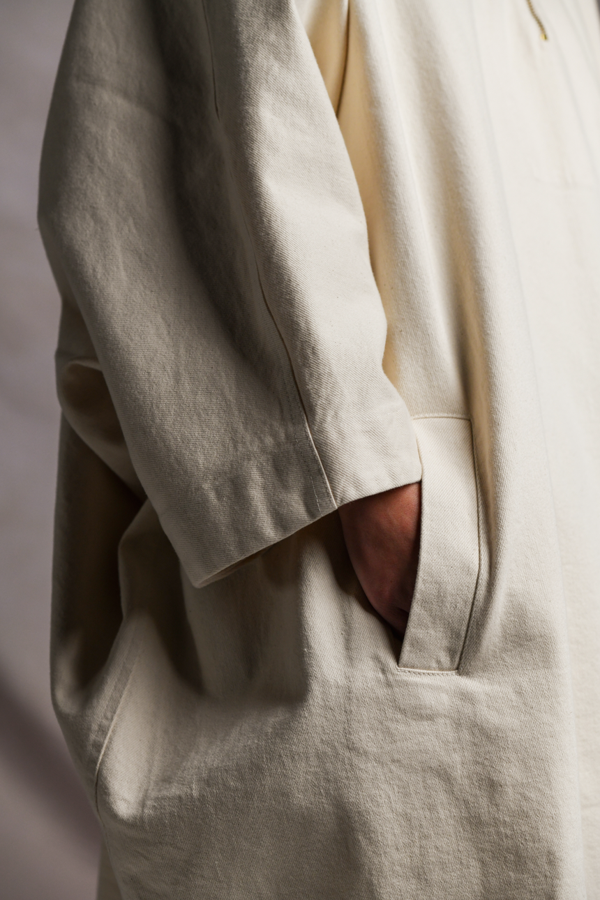 Close up view of front pockets of Mónica Cordera chunky hooded poncho in natural.